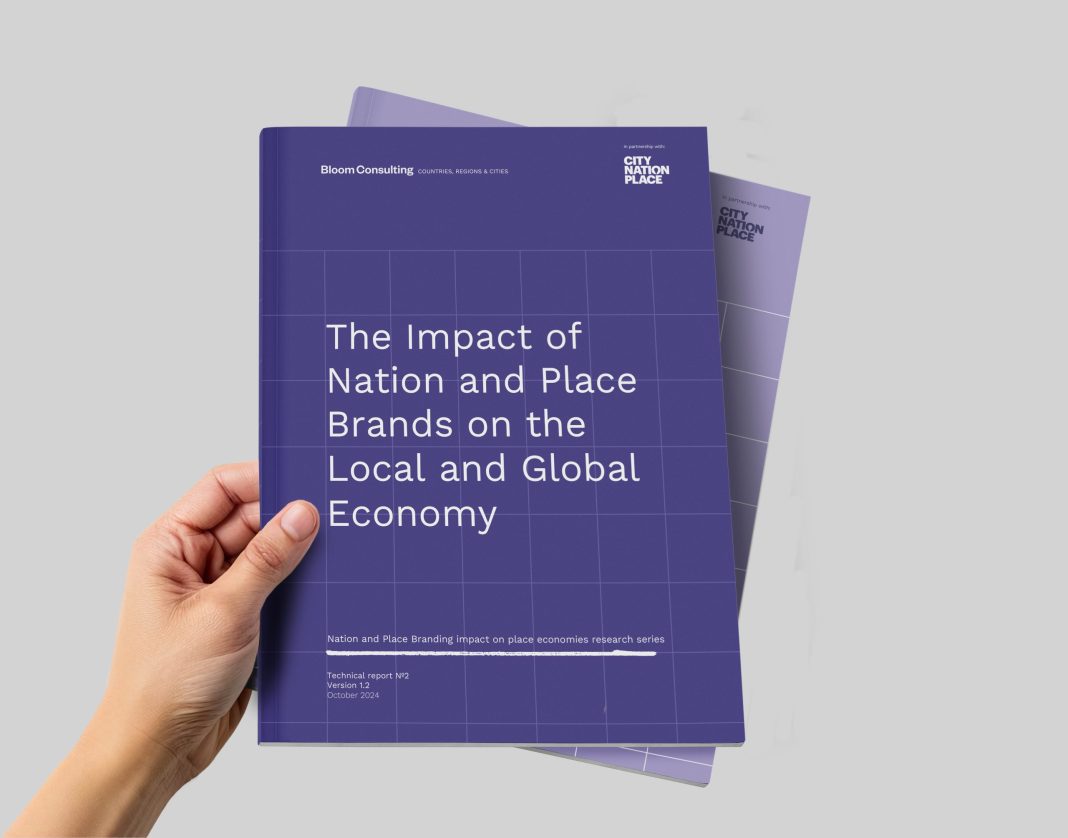 Hand Holding Blank White Paper Sheet. Bloom Consulting study The Impact of Nation and Place Brands on the Local and Global Economy